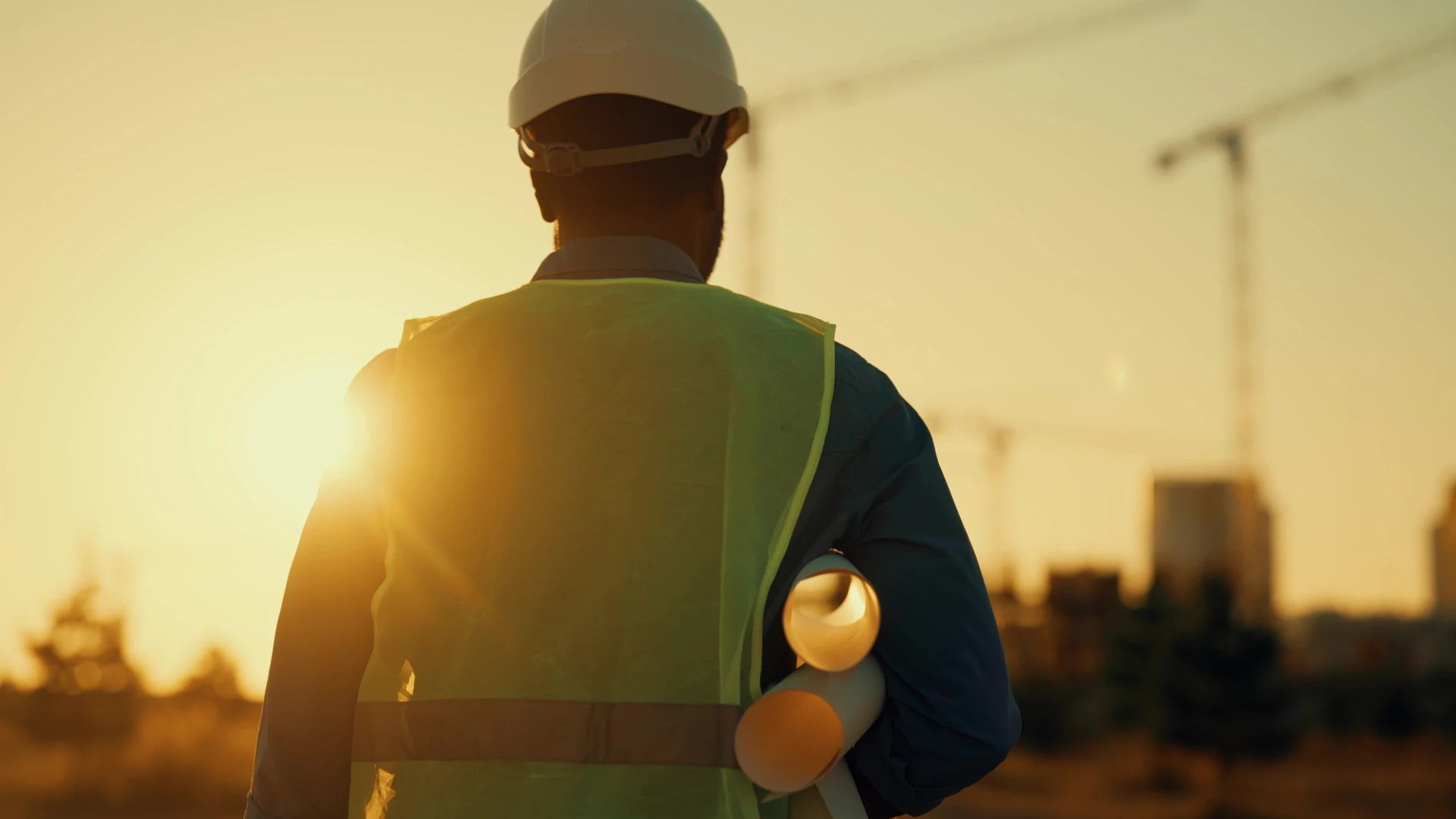 Ouvrier en équipement de sécurité travaillant sur échafaudage devant façade d'immeuble