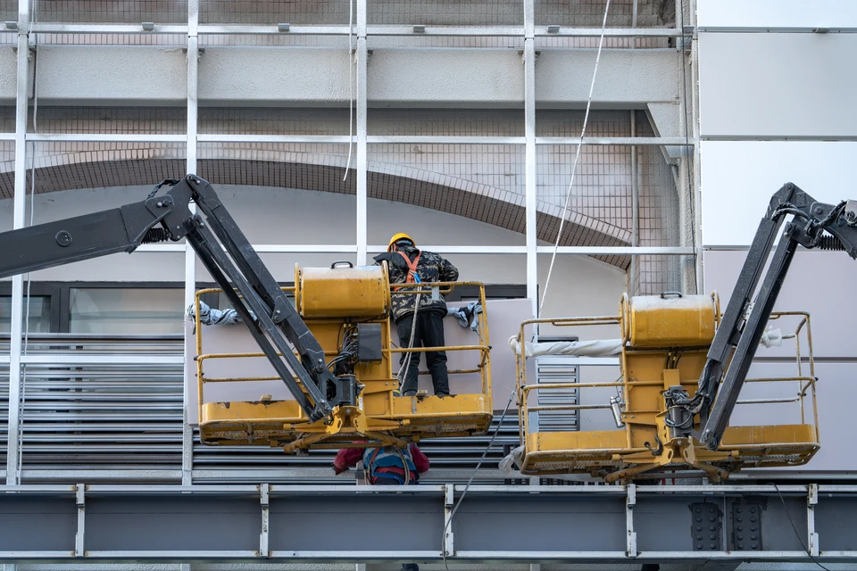 Un travailleur portant des gants aligne soigneusement des planches de bois tout en construisant un pont, avec des outils et des matériaux comme une perceuse et des vis visibles à la surface