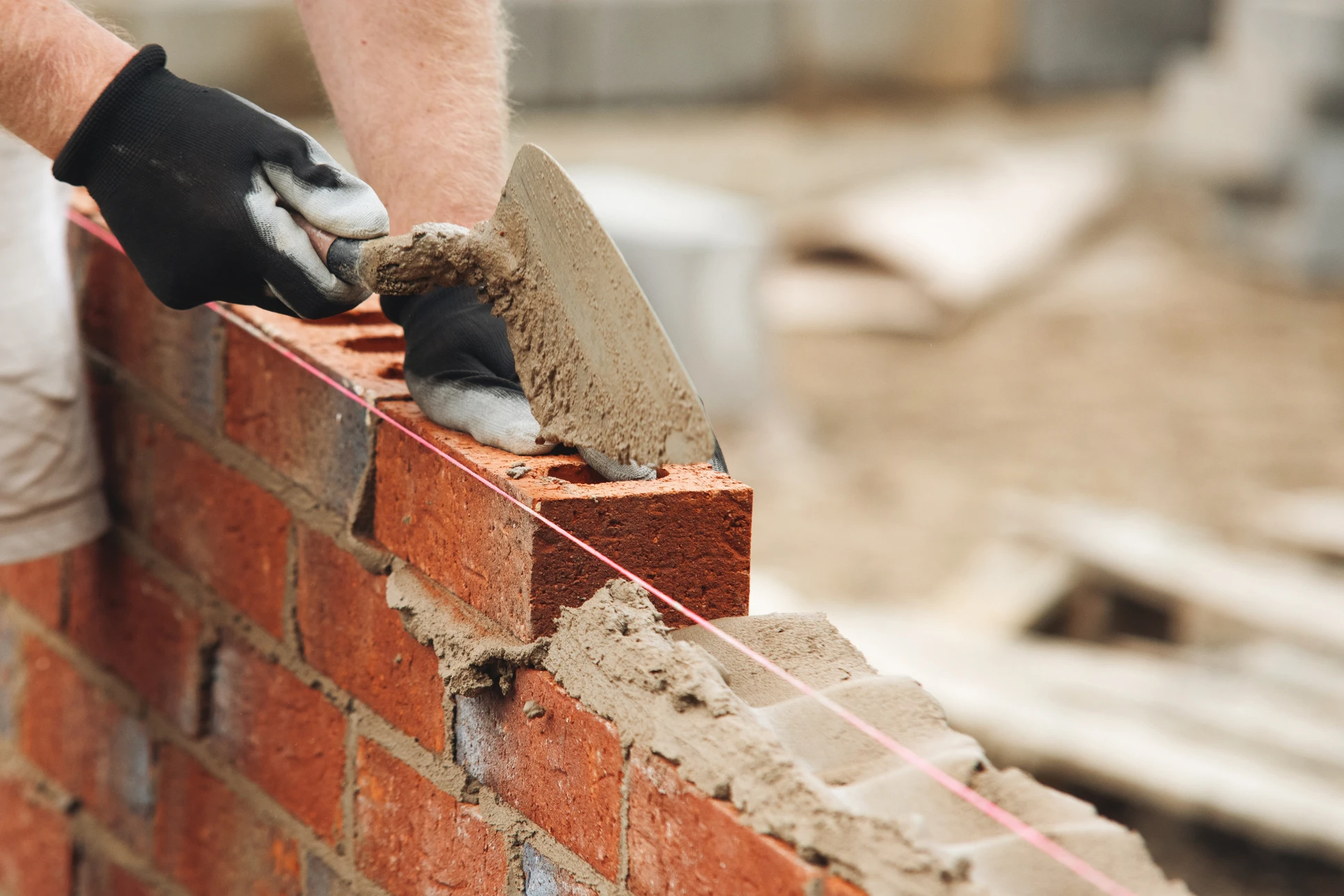Chantier de construction résidentielle en cours avec ouvriers assemblant la structure d'une maison individuelle