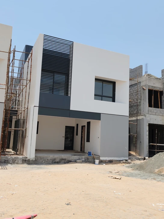 Scène extérieure avec nacelle élévatrice articulée orange en position élevée contre un ciel bleu nuageux