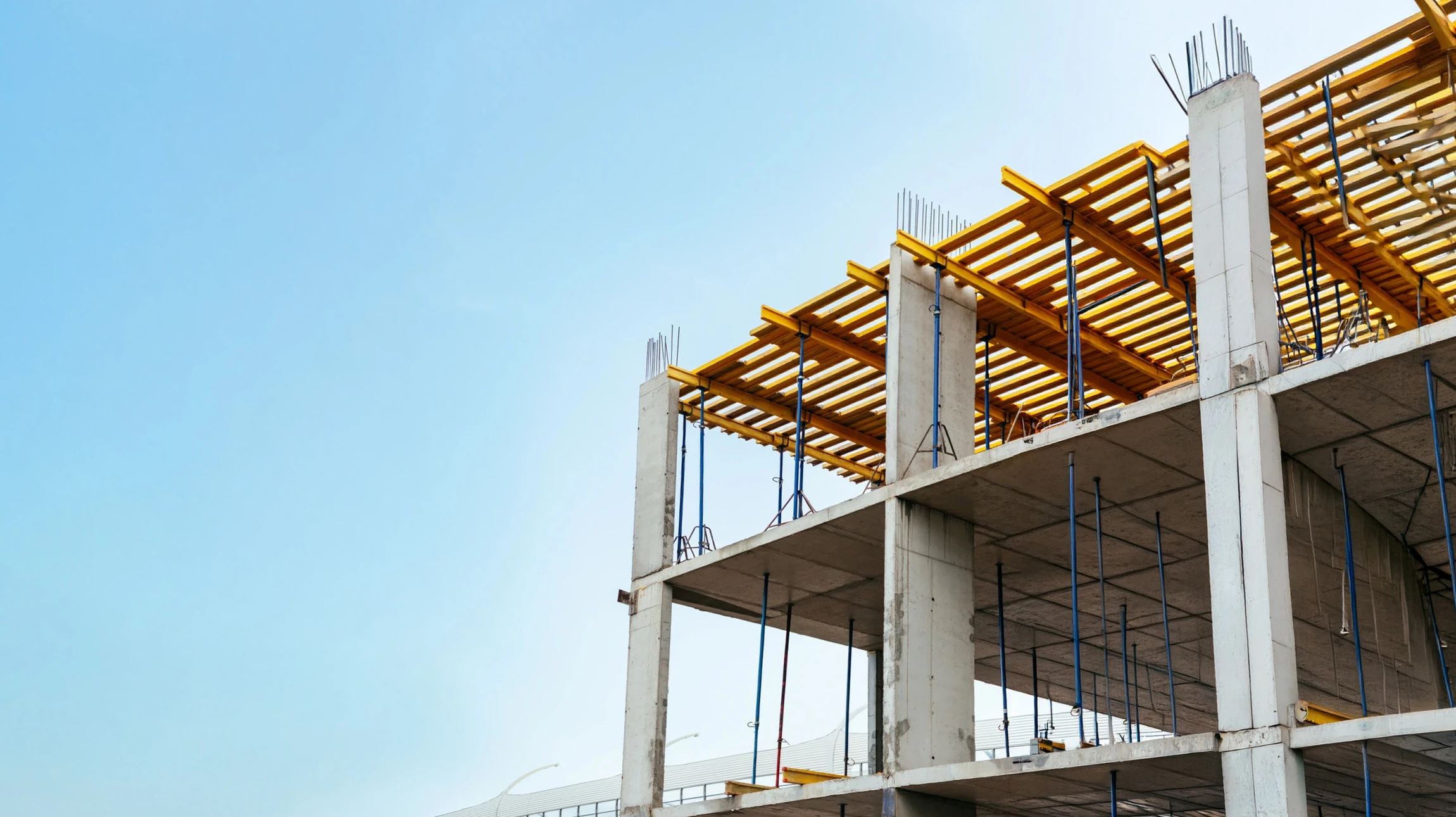 Chantier de construction en extérieur avec ouvriers en casques de sécurité travaillant sur dalle béton armé