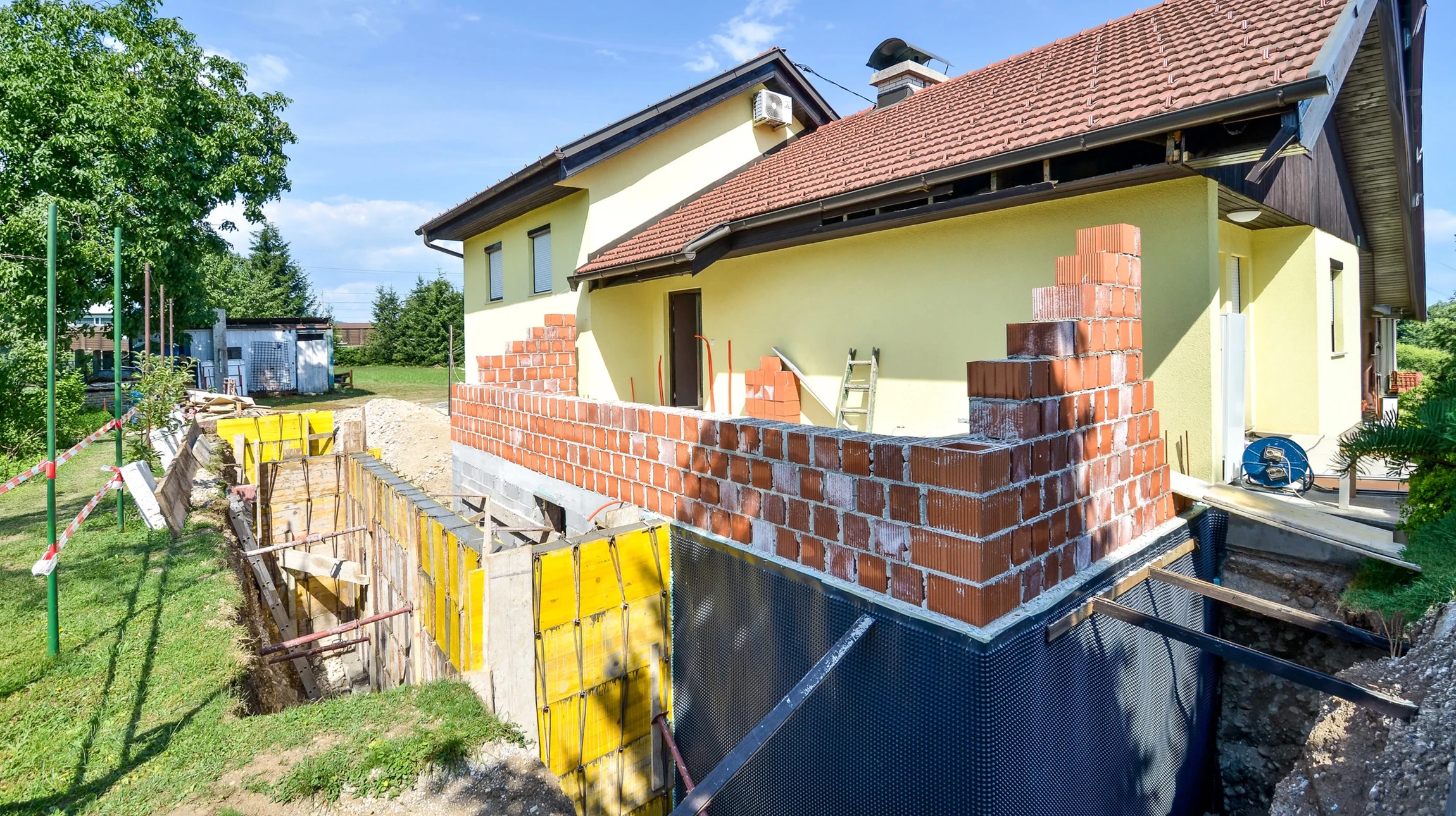 Chantier de construction résidentielle en phase de fondation avec ouvriers posant des blocs de béton